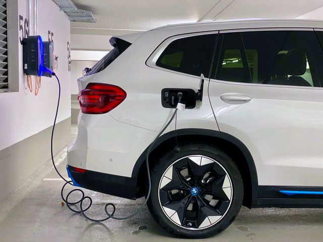 Podpięty do ładowania elektryczny SUV marki BMW w podziemnym parkingu