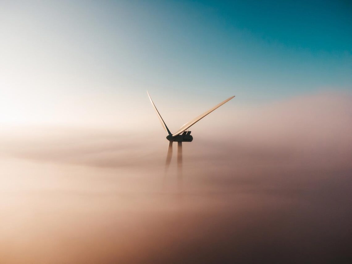 Zdjęcie wirnika turbiny wiatrowej wyłaniającego się ponad chmury