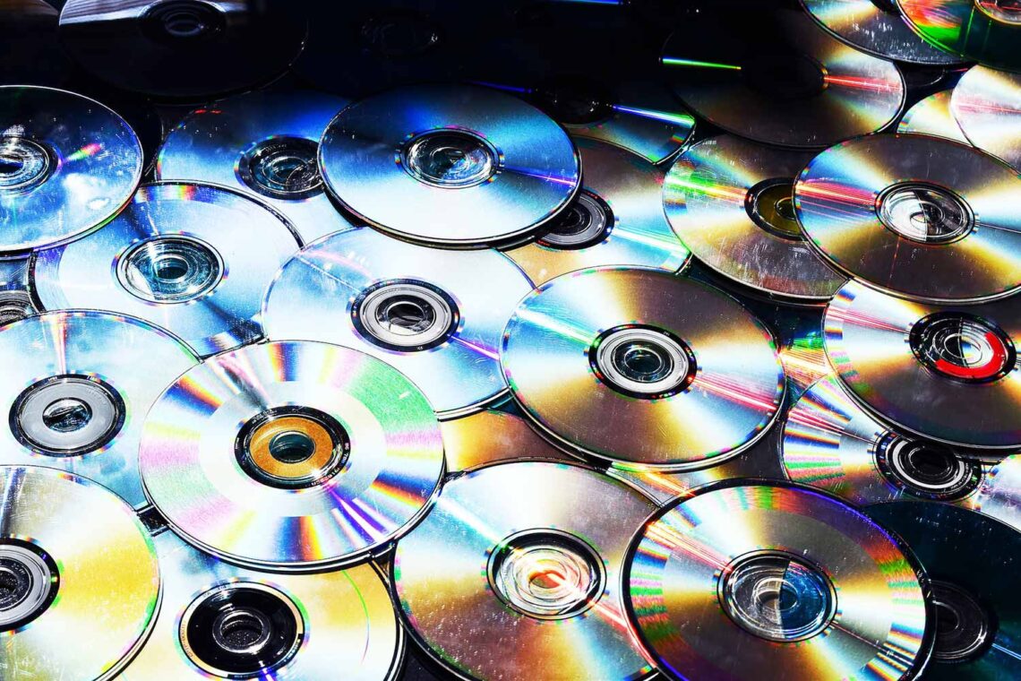 Zdjęcie kilkunastu zużytych, płyt CD ustawionych błyszczącą warstwą do góry